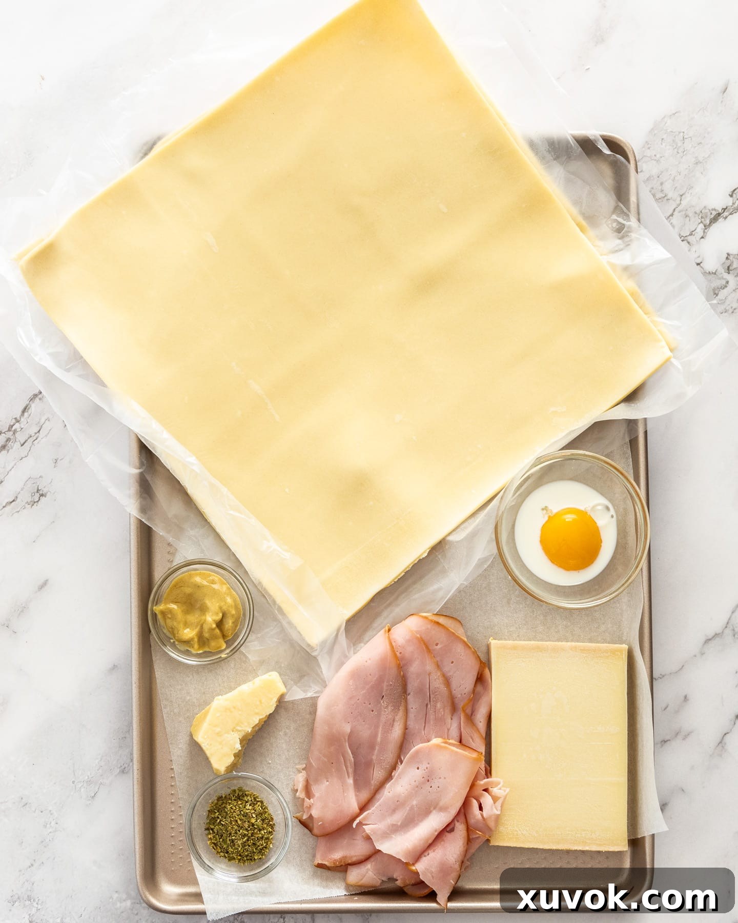 Ingredients for tart soleil on a baking tray, showcasing ham, cheese, and puff pastry.