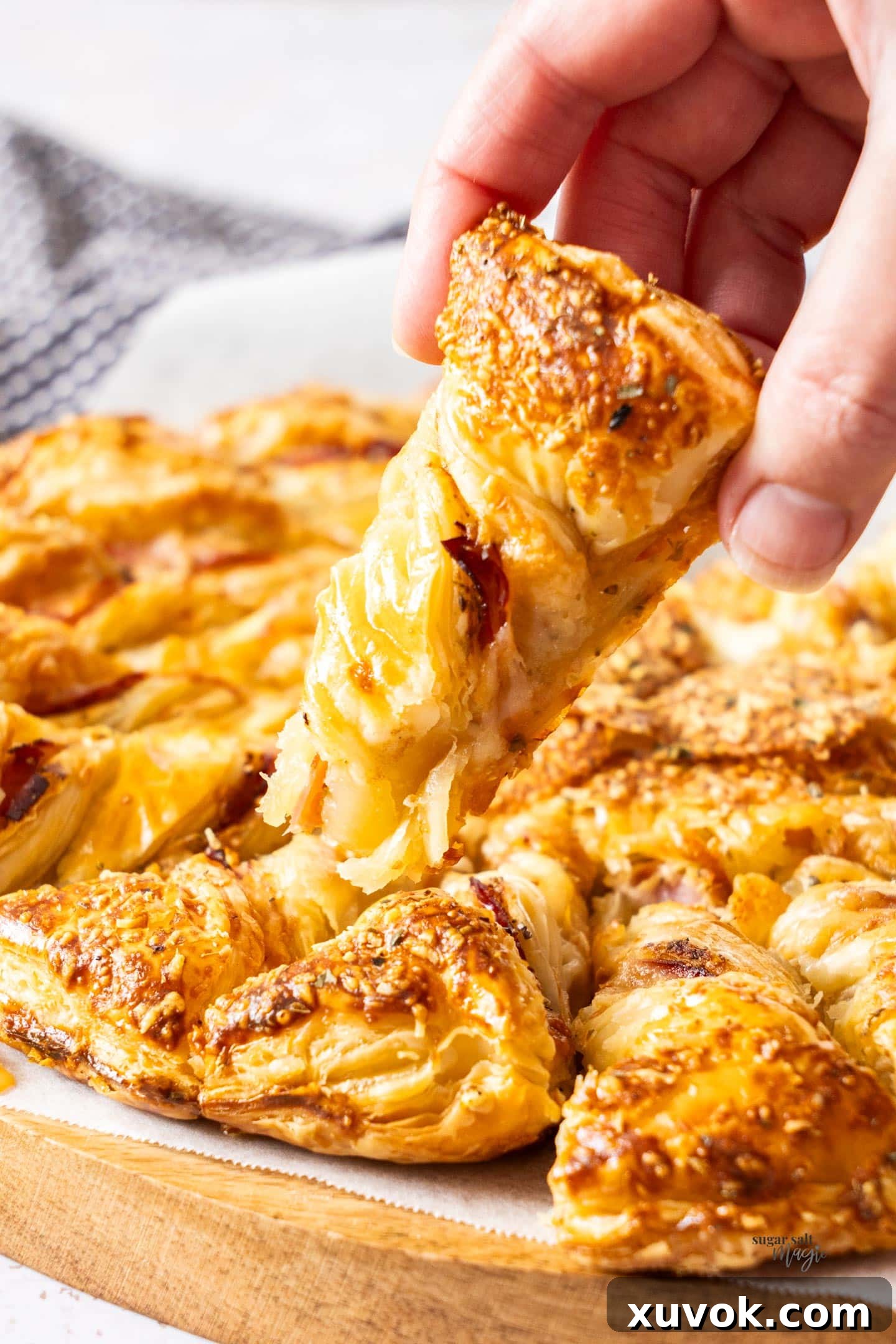 A hand holding a piece of tart soleil, showing the twisted pastry and filling.