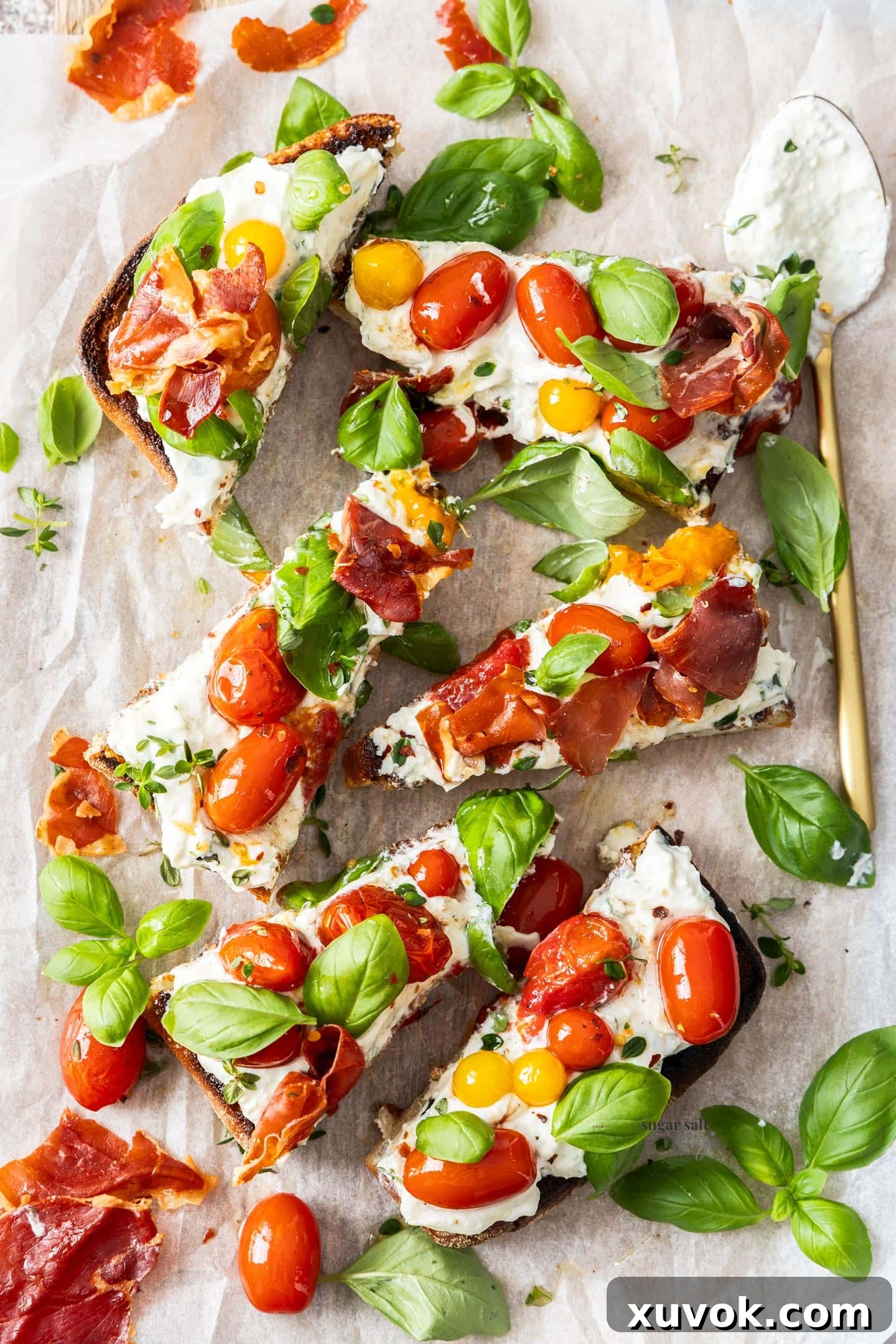 A close-up of a fully assembled Slow Roasted Tomato Bruschetta, pre-sliced into individual servings, showcasing the vibrant layers of toppings.