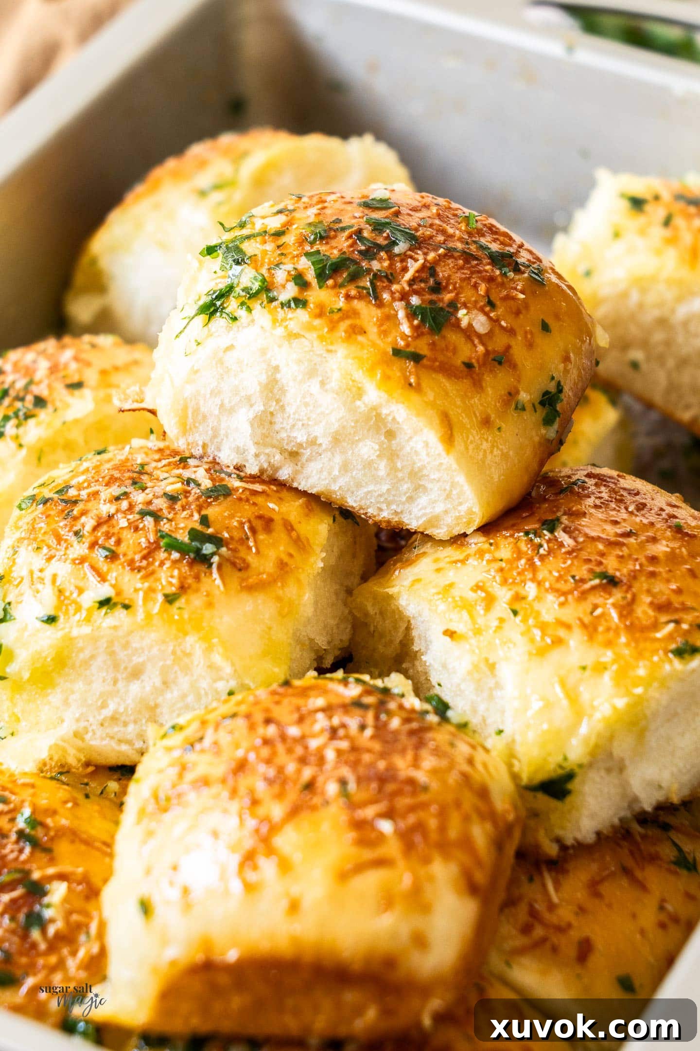 A baking pan overflowing with a generous pile of soft, fluffy garlic dinner rolls, ready to be devoured.