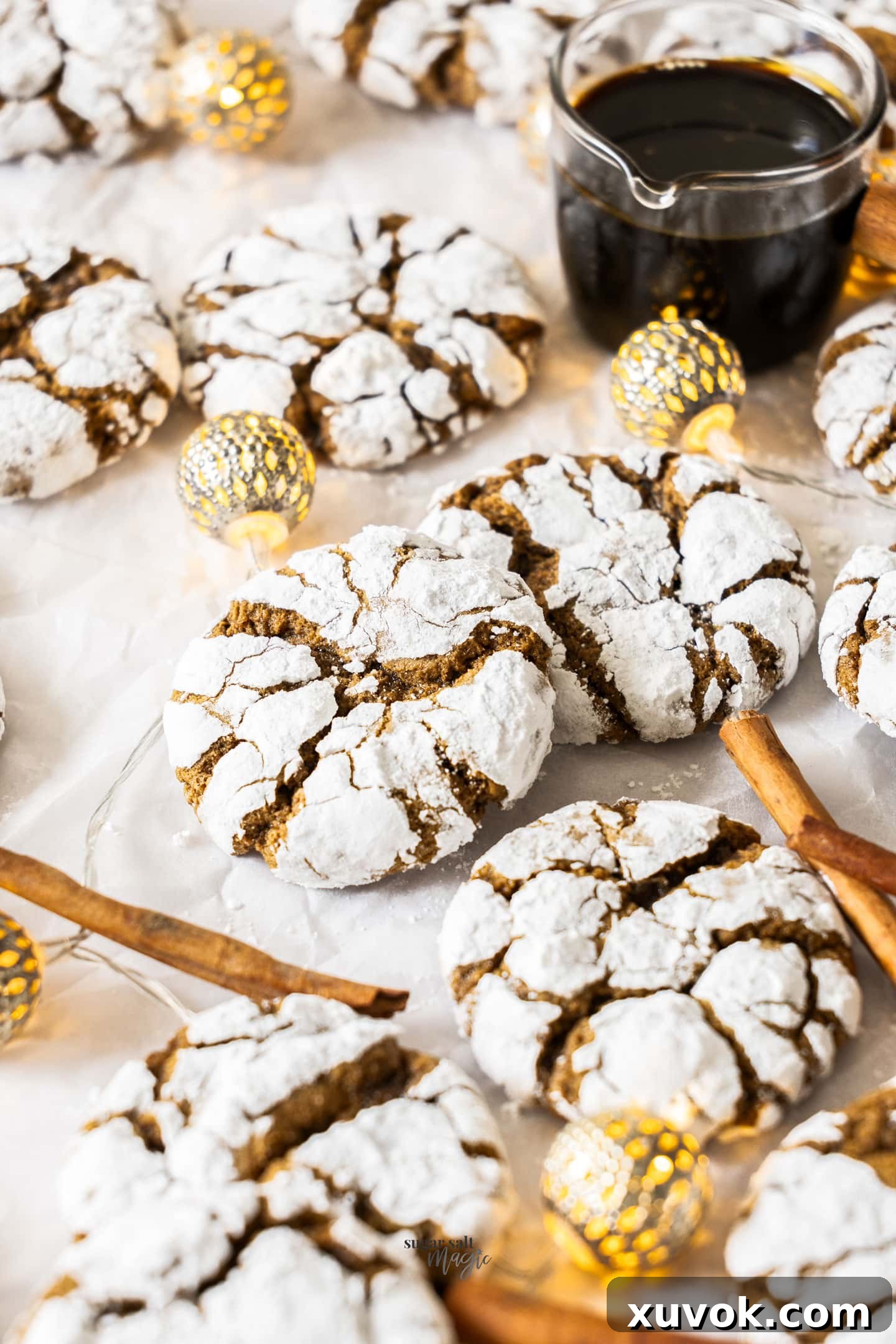 Two gingerbread crinkle cookies, one leaning on the other, with a rustic jug of molasses in the soft-focus background, evoking a warm, inviting holiday scene.