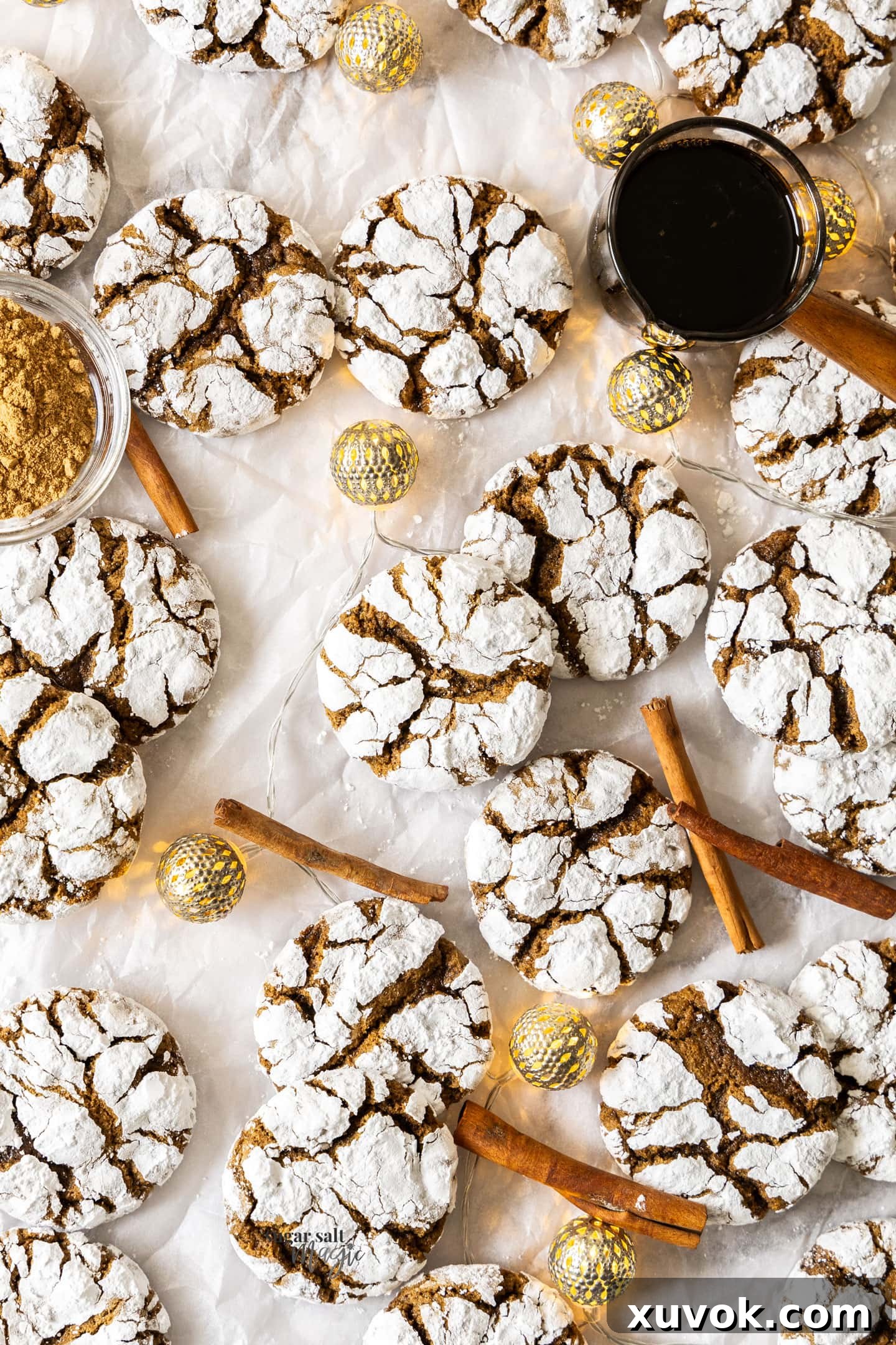 A top-down view of a freshly baked batch of gingerbread crinkle cookies on a cooling rack, with a jug of molasses in the background, highlighting their festive appeal.