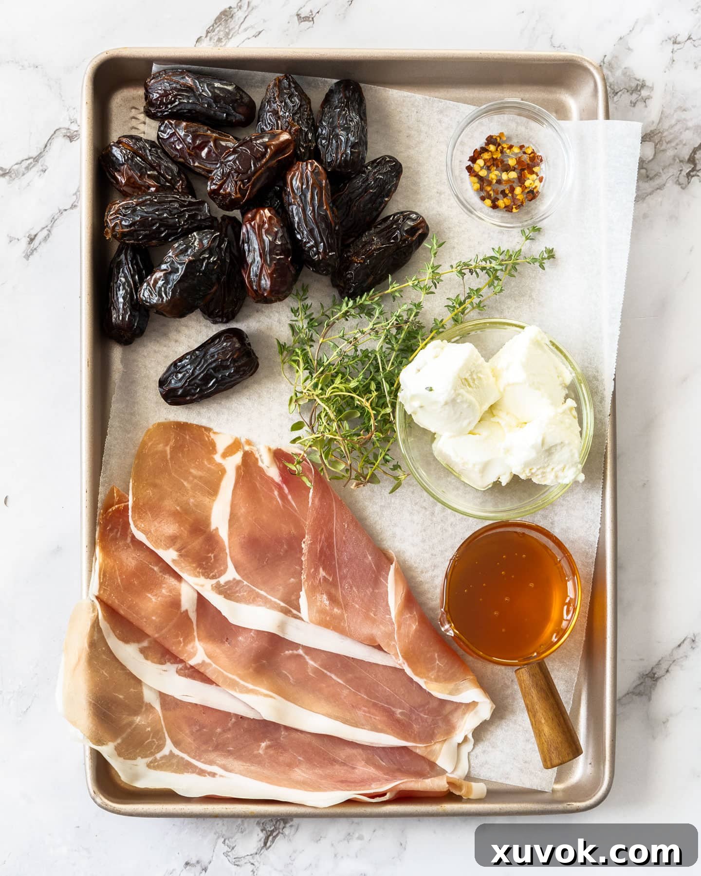 Assortment of fresh ingredients for prosciutto wrapped dates, including dates, goat cheese, prosciutto, and thyme.