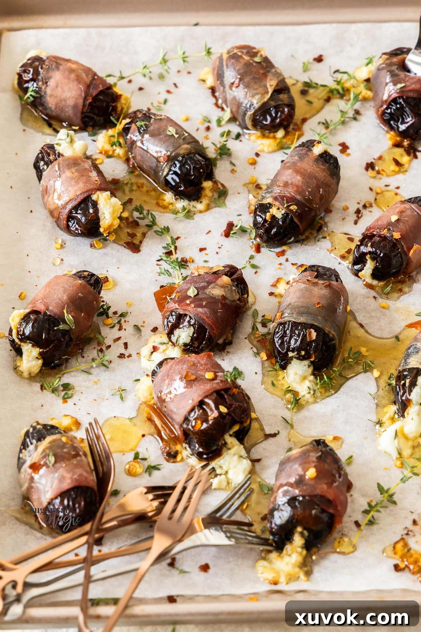 A whole batch of perfectly baked, stuffed dates on a baking tray, glistening with honey.