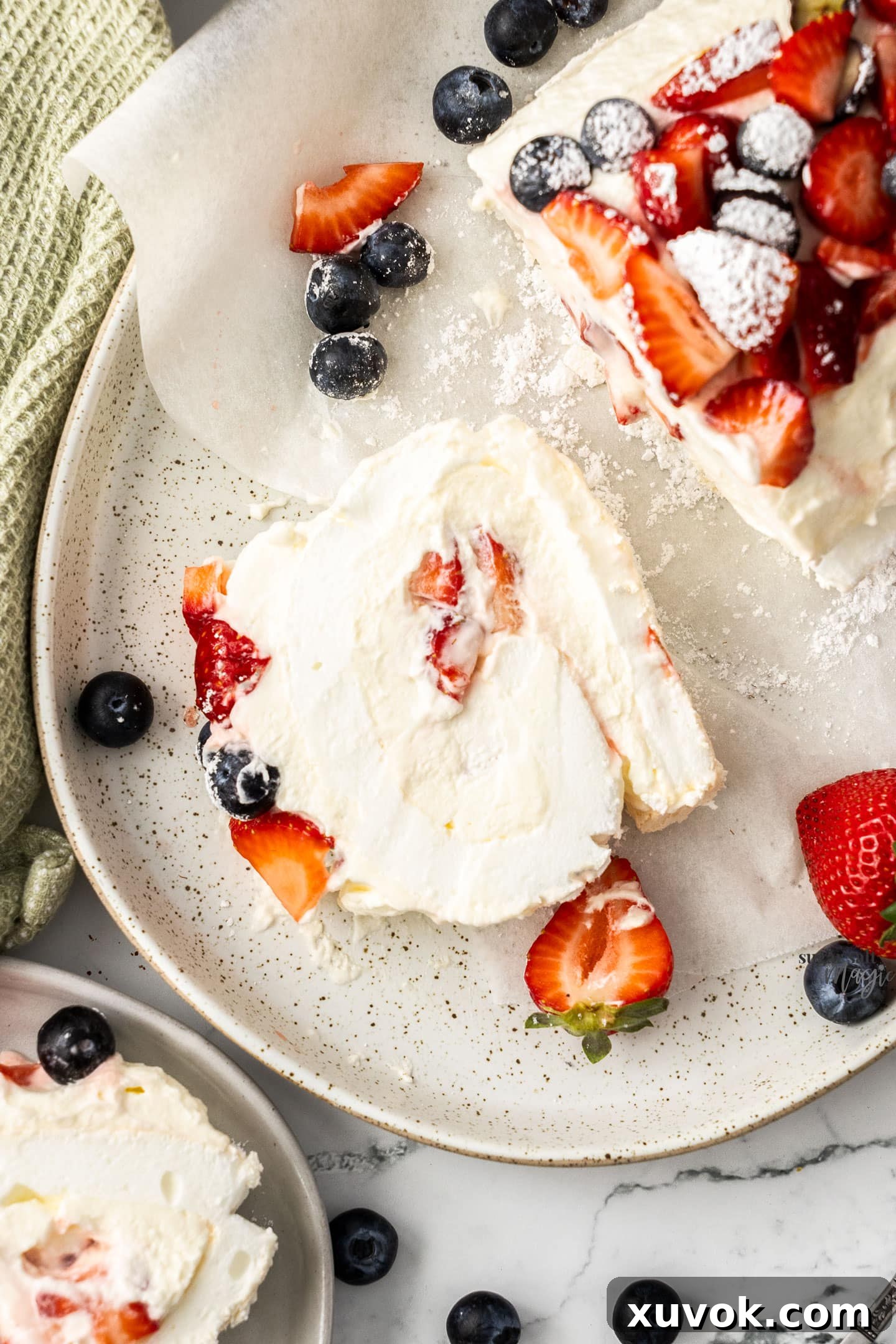 Top down view of a slice of meringue roulade showing the layers of meringue, cream, and berries.