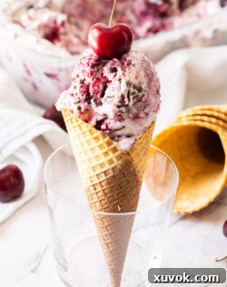 A waffle cone with scoops of Black Forest Ice Cream standing in a glass, ready to be enjoyed.