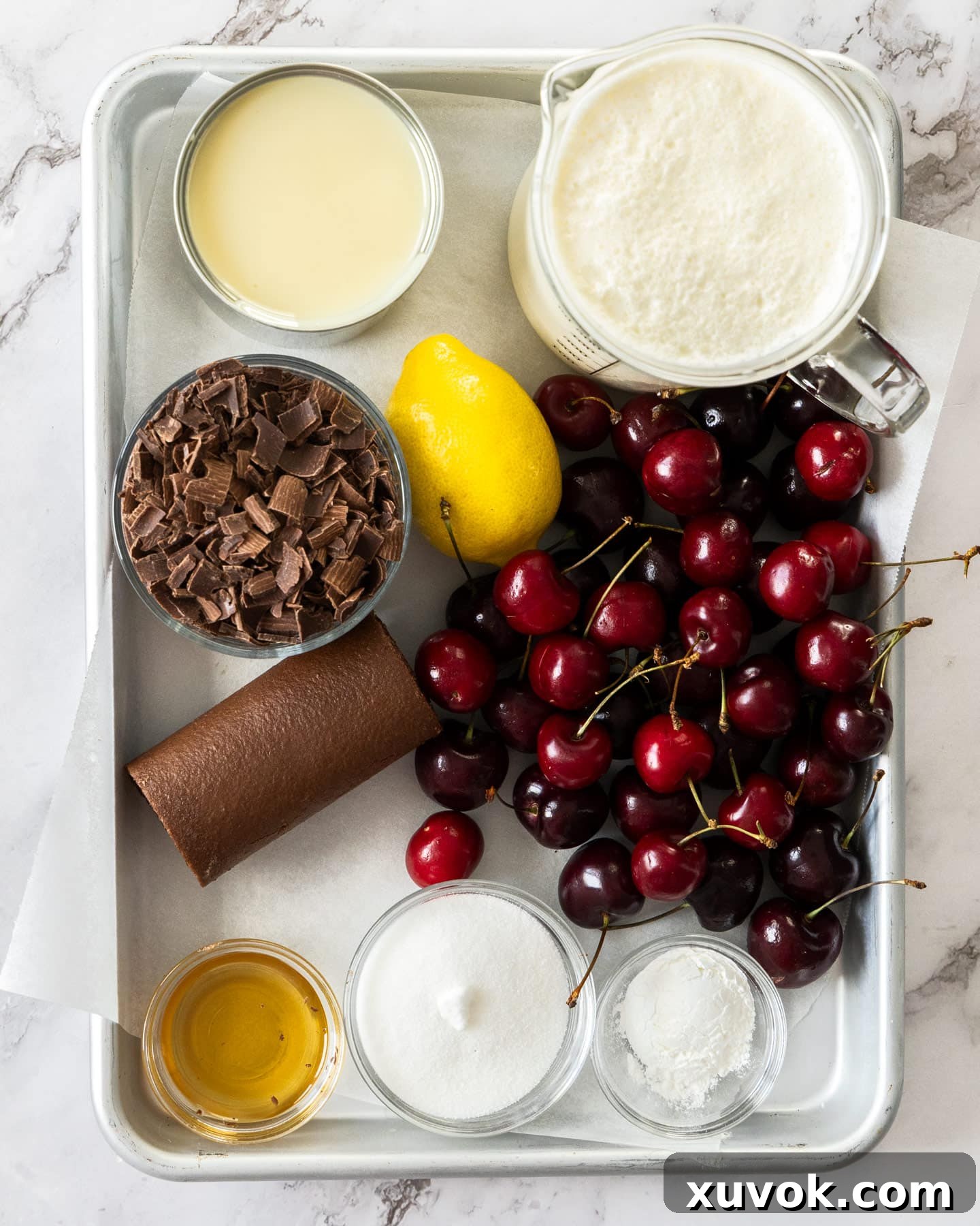 A curated display of ingredients for Black Forest Ice Cream, including fresh cherries, chocolate, cream, and condensed milk.