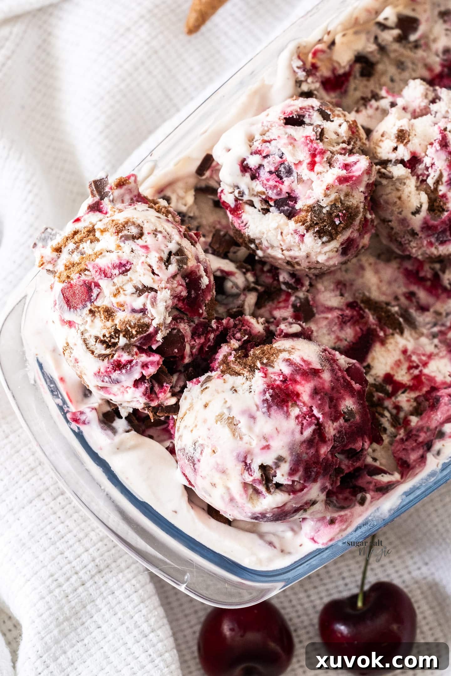 A top-down view of scoops of Black Forest Ice Cream beautifully presented in a glass dish, highlighting the swirls of cherry and chocolate.