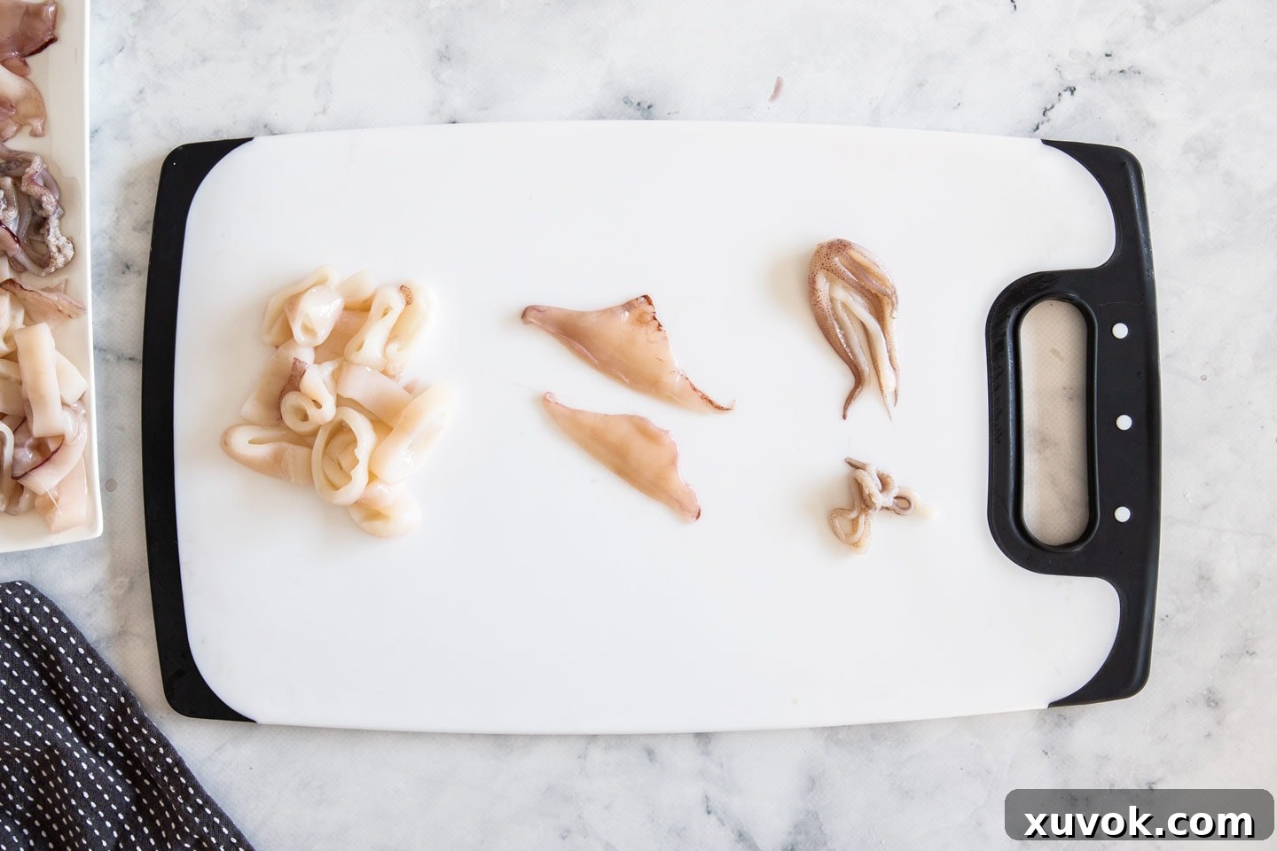 Cleaned squid, both sliced into rings and with tentacles, neatly arranged on a chopping board.