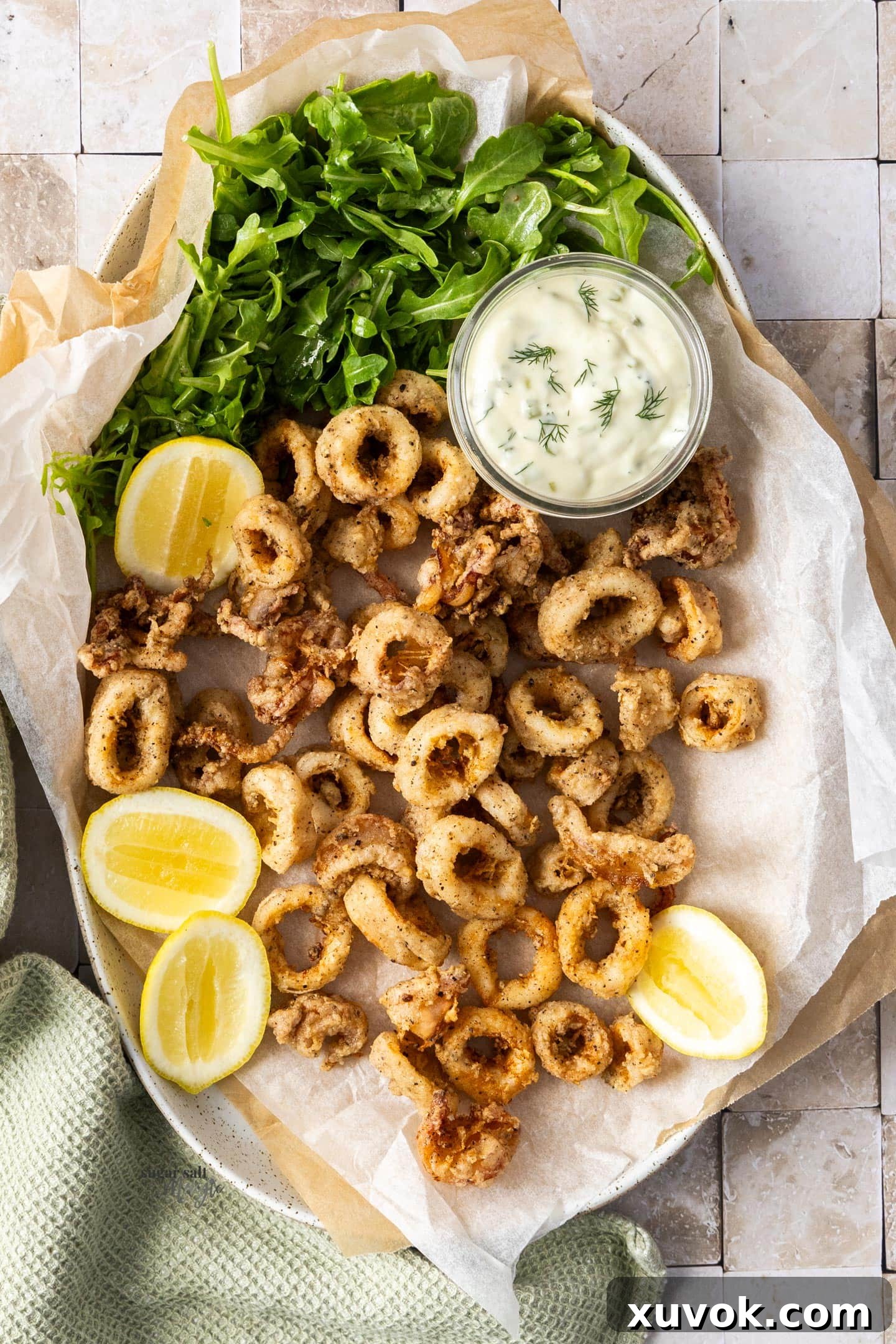 Top down view of salt and pepper calamari with lemons and mayonnaise.