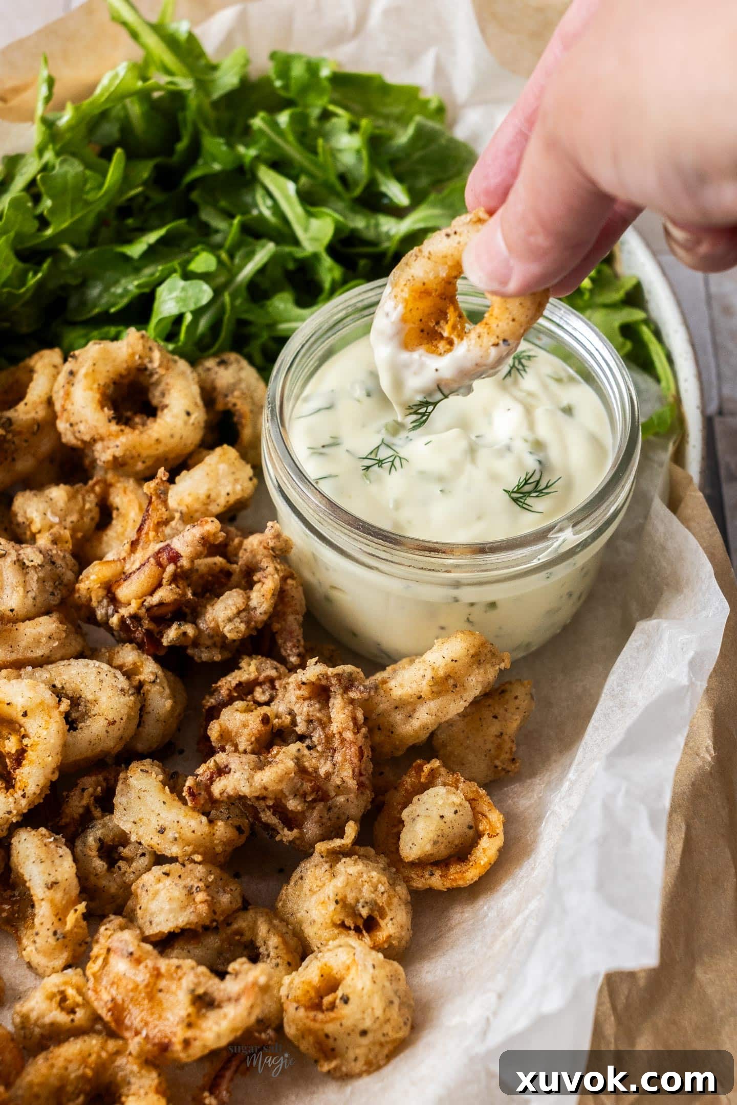 A piece of calamari being dipped into mayonnaise.