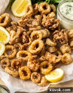 A pile of salt and pepper calamari with lemon wedges.