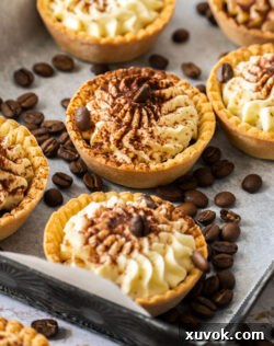 A batch of tartlets on a metal tray, surrounded by coffee beans.