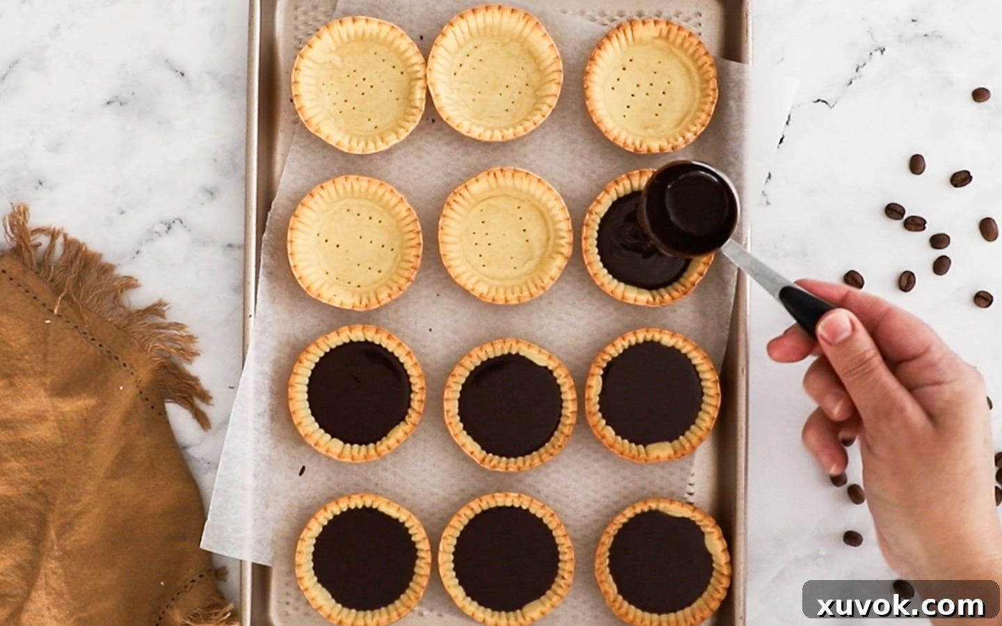 Adding ganache to baked tartlet shells.