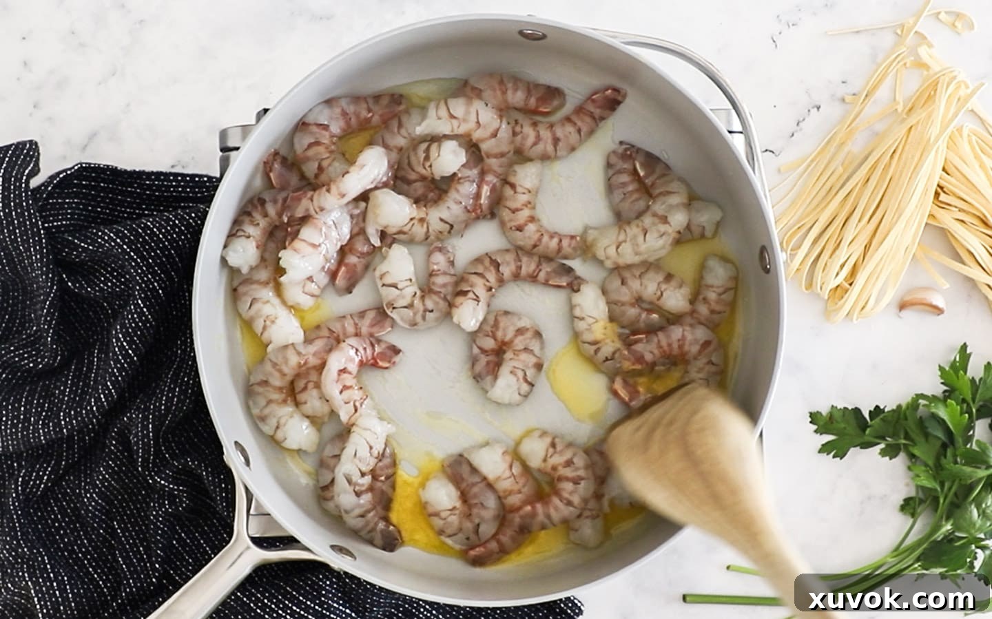 Raw prawns sizzling in butter and olive oil in a pan, ready to be cooked.