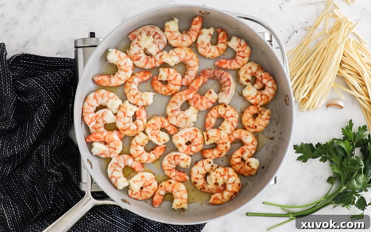 Perfectly cooked, pink prawns in a pan, removed and ready to be set aside.