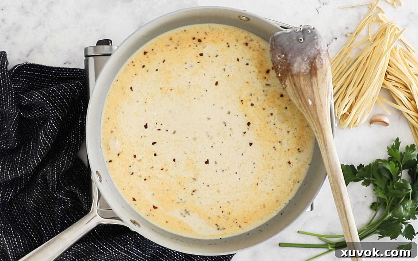 Thickened cream being added to the garlic and pepper base in a pan, forming the sauce.