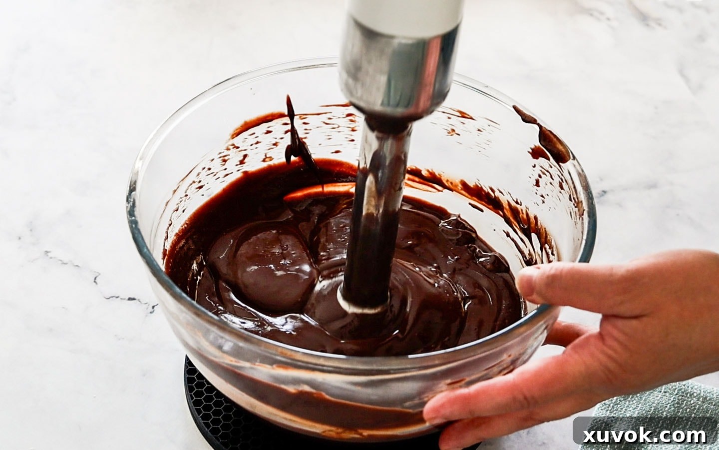 Using an immersion blender to smooth the cremeux, keeping the blender head submerged to avoid air bubbles.