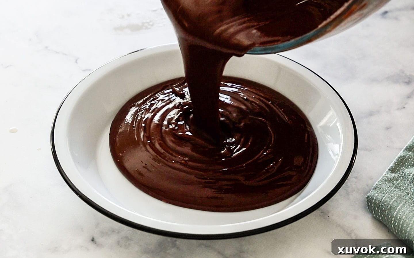 Pouring the hot cremeux into a dish, ready to be covered and chilled for setting.