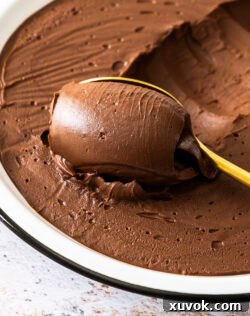 A scoop of chocolate cremeux on a gold spoon, looking rich and inviting.