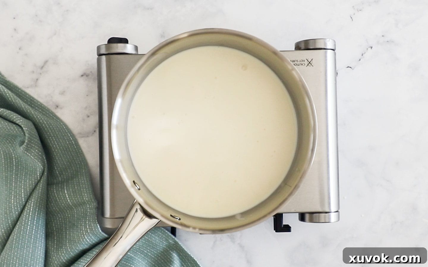 Heating milk and cream in a saucepan on the stove, with small bubbles starting to form.
