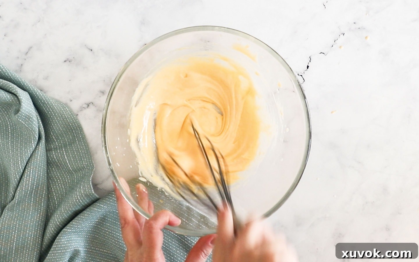 Whisking egg yolks and sugar together in a bowl until light and fluffy.