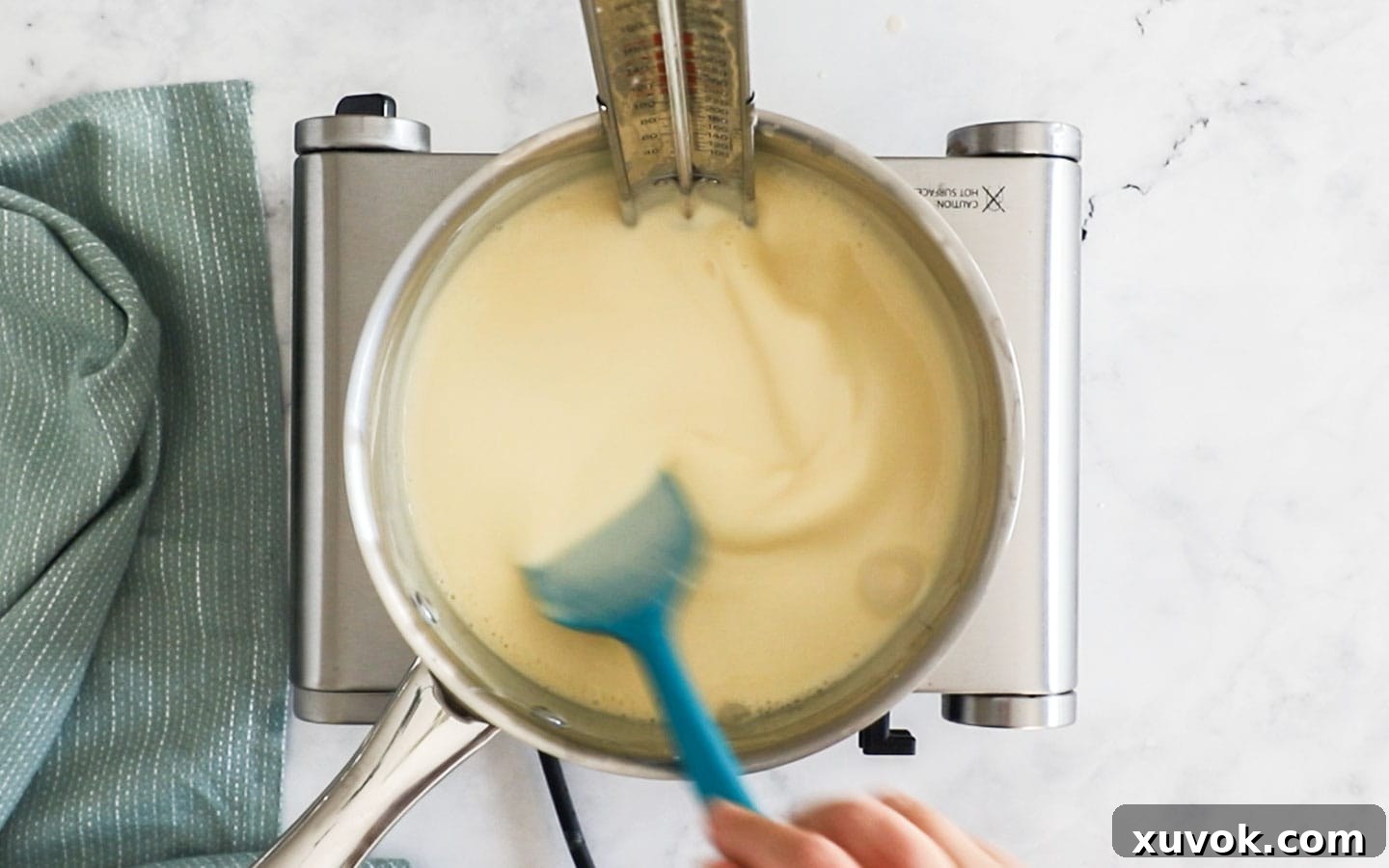 Stirring creme anglaise on the stovetop, demonstrating the thickening process and consistent stirring.