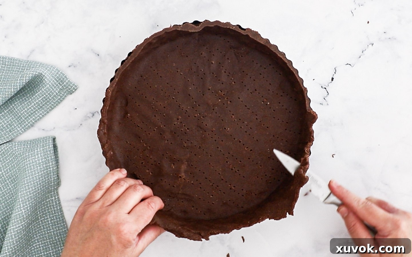 Slicing the overhang off the tart shell.
