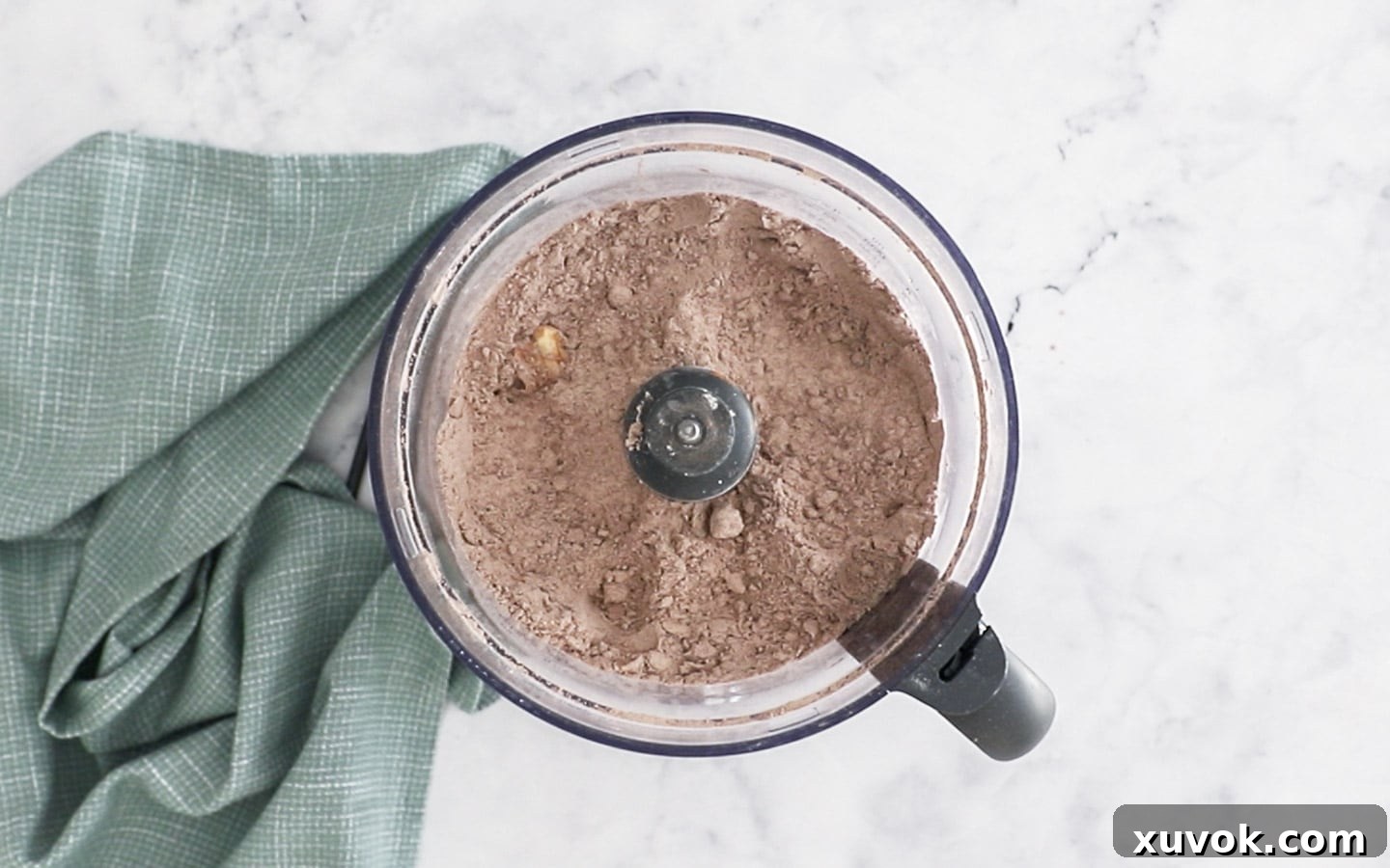 Showing the butter cut into the flour and cocoa in a food processor bowl.