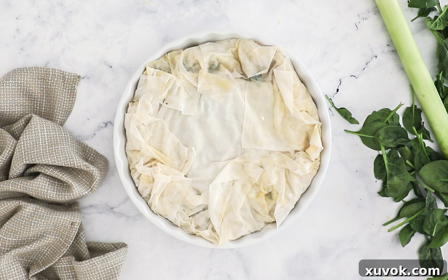 The overhanging filo pastry sheets are folded inwards, covering the chicken filling.
