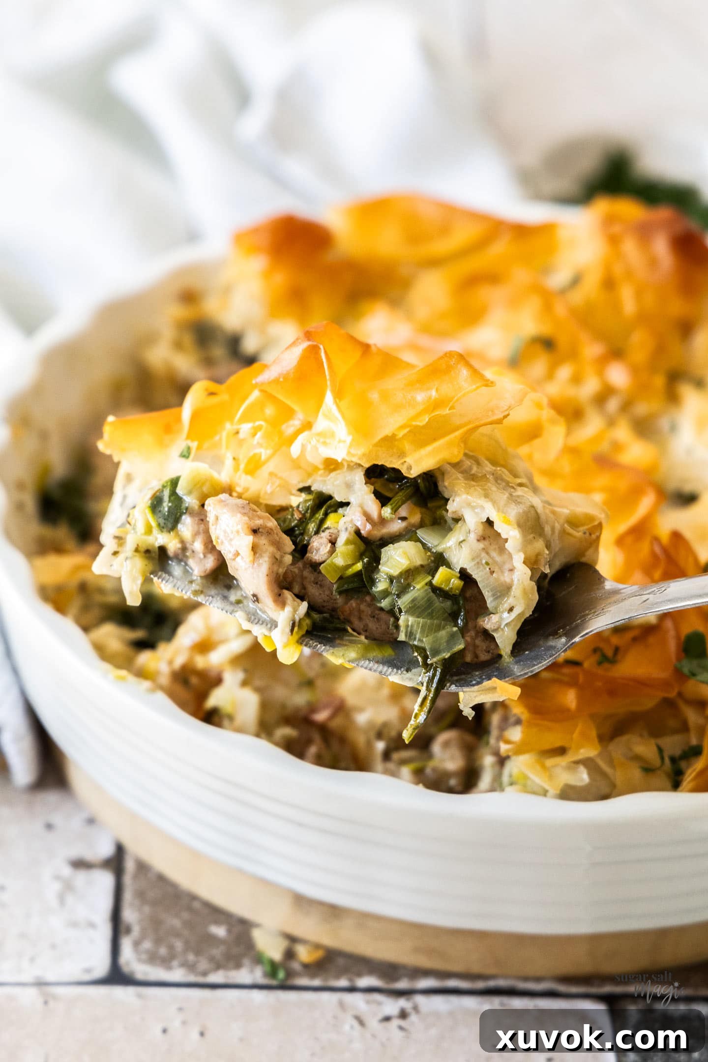 A perfectly golden slice of chicken filo pie, showing the flaky pastry and creamy filling, served on a pie server.