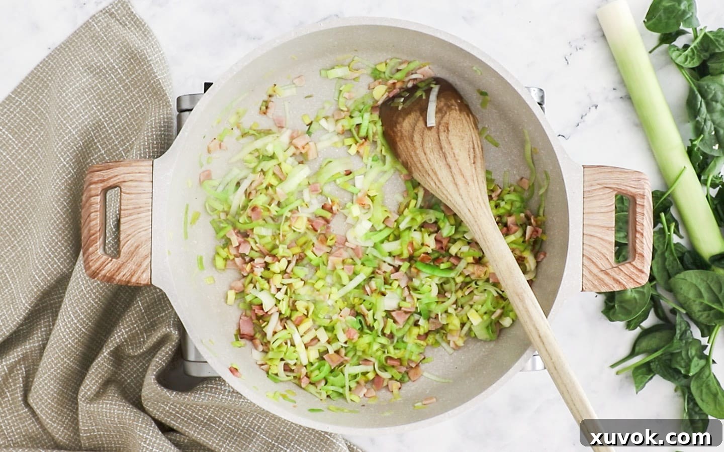 Diced bacon and thinly sliced leeks cooking in a pan until softened and aromatic.