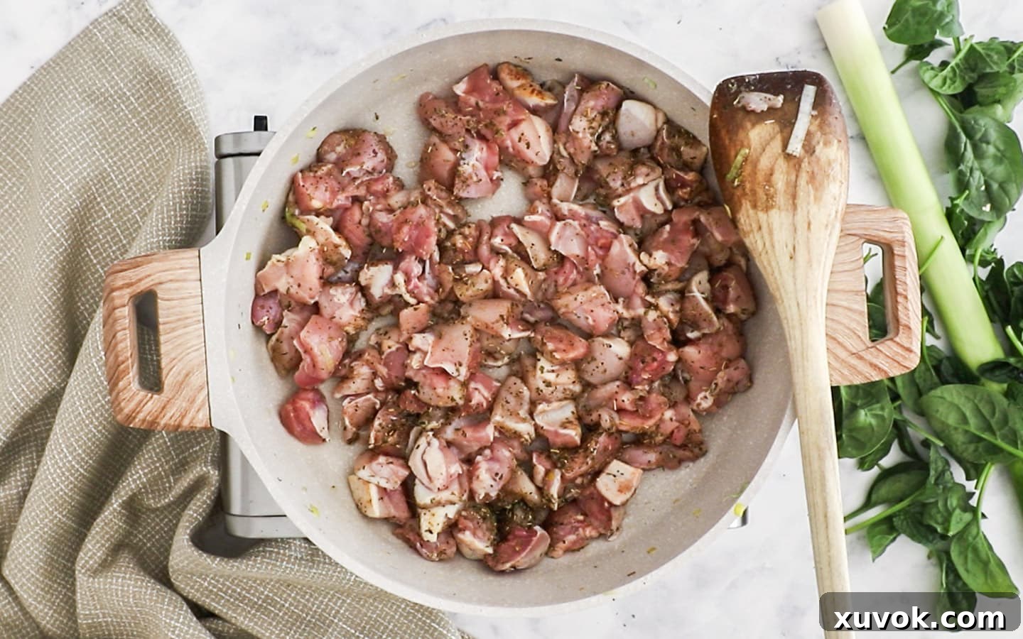 Cubed chicken thighs being added to a hot pan, ready to be seasoned and cooked.