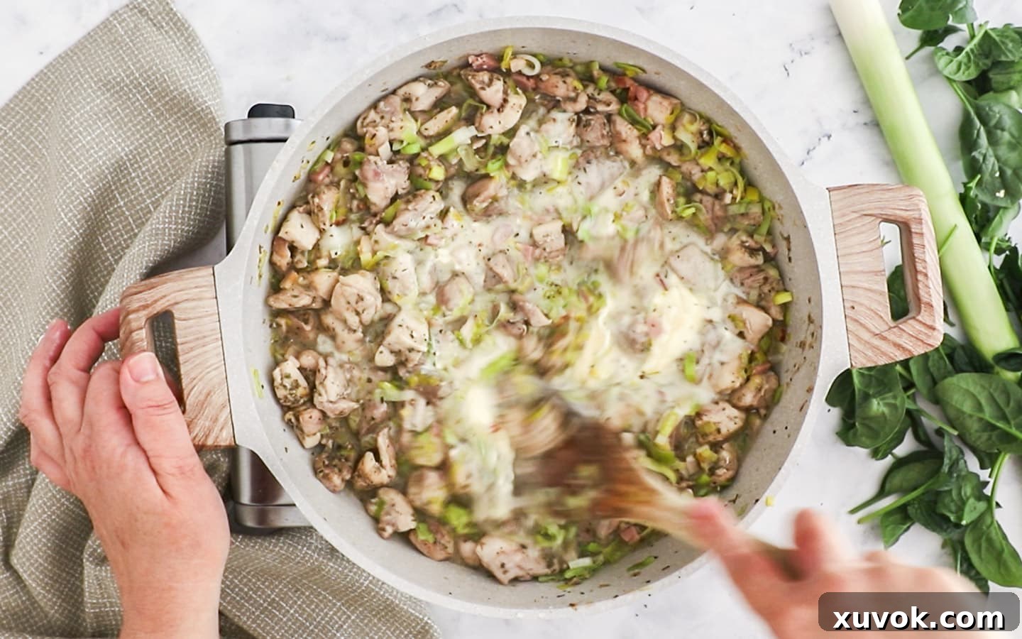 Crème fraîche being stirred into the thick, creamy chicken pie filling.