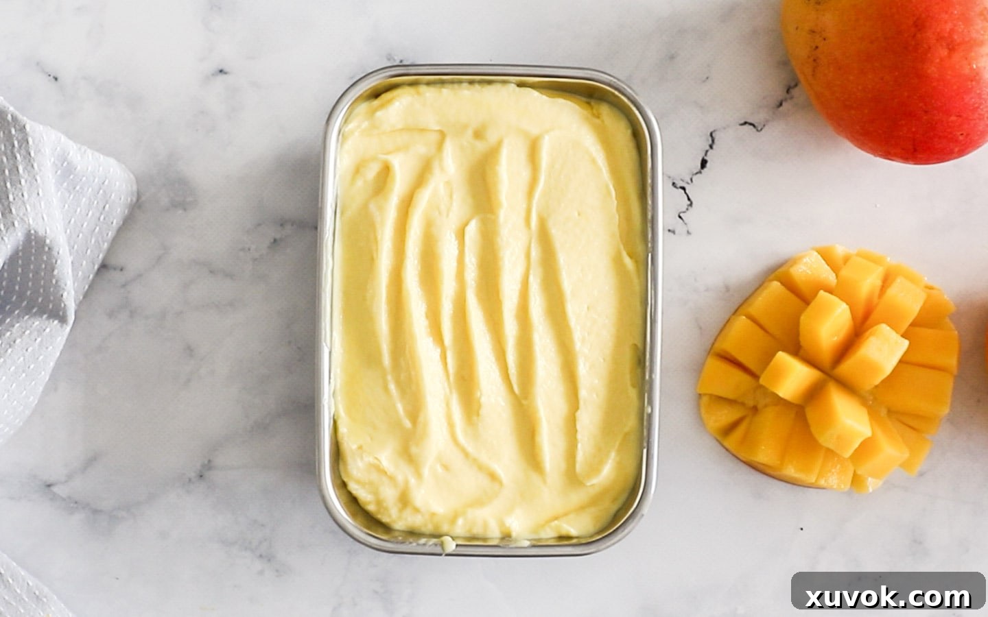 Mango gelato scooped into a metal tin, ready for freezing.