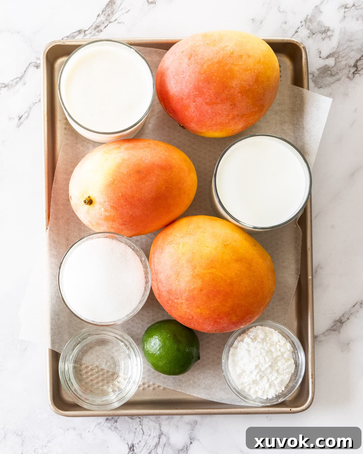 Fresh ingredients for mango gelato laid out on a baking tray.
