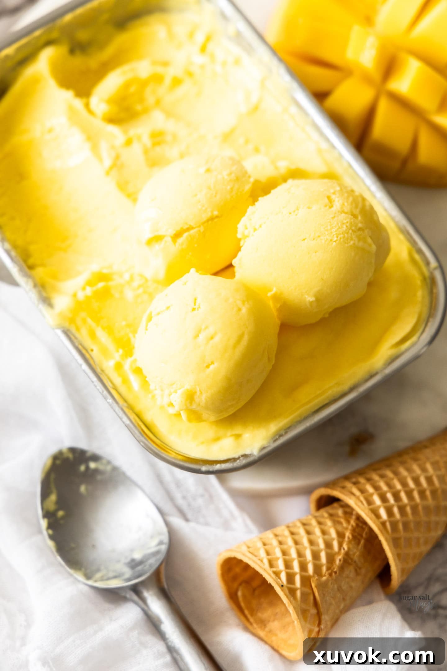 Multiple scoops of mango gelato stacked on top of a pan, showcasing its creamy texture.