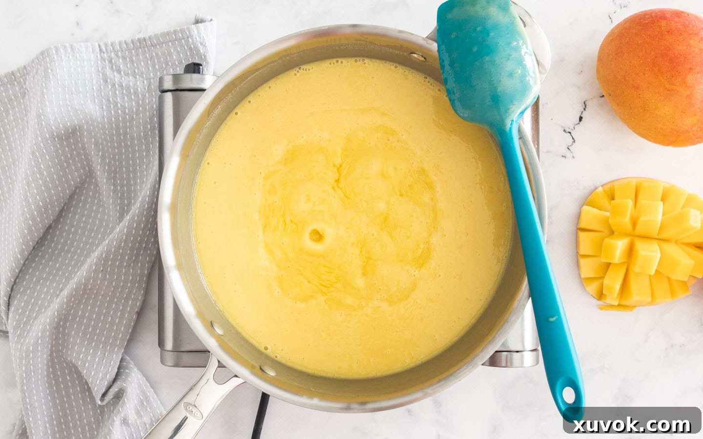 The mango custard mixture bubbling gently in a saucepan.