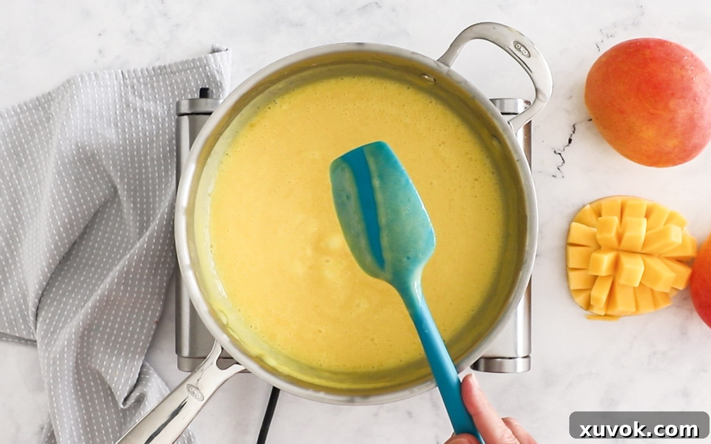 Mango custard mixture coating the back of a spoon, showing its thick consistency.