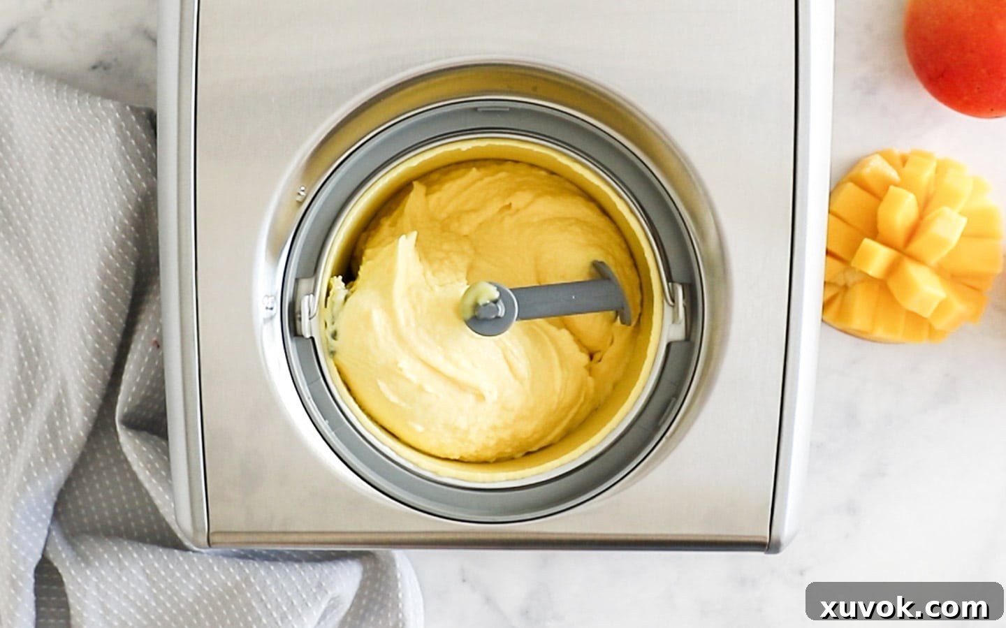 Top down view of mango gelato being churned in an ice cream machine.