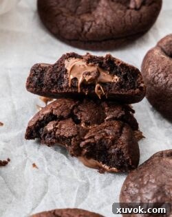 Closeup of a chocolate nutella cookie broken in half showing the gooey inside.