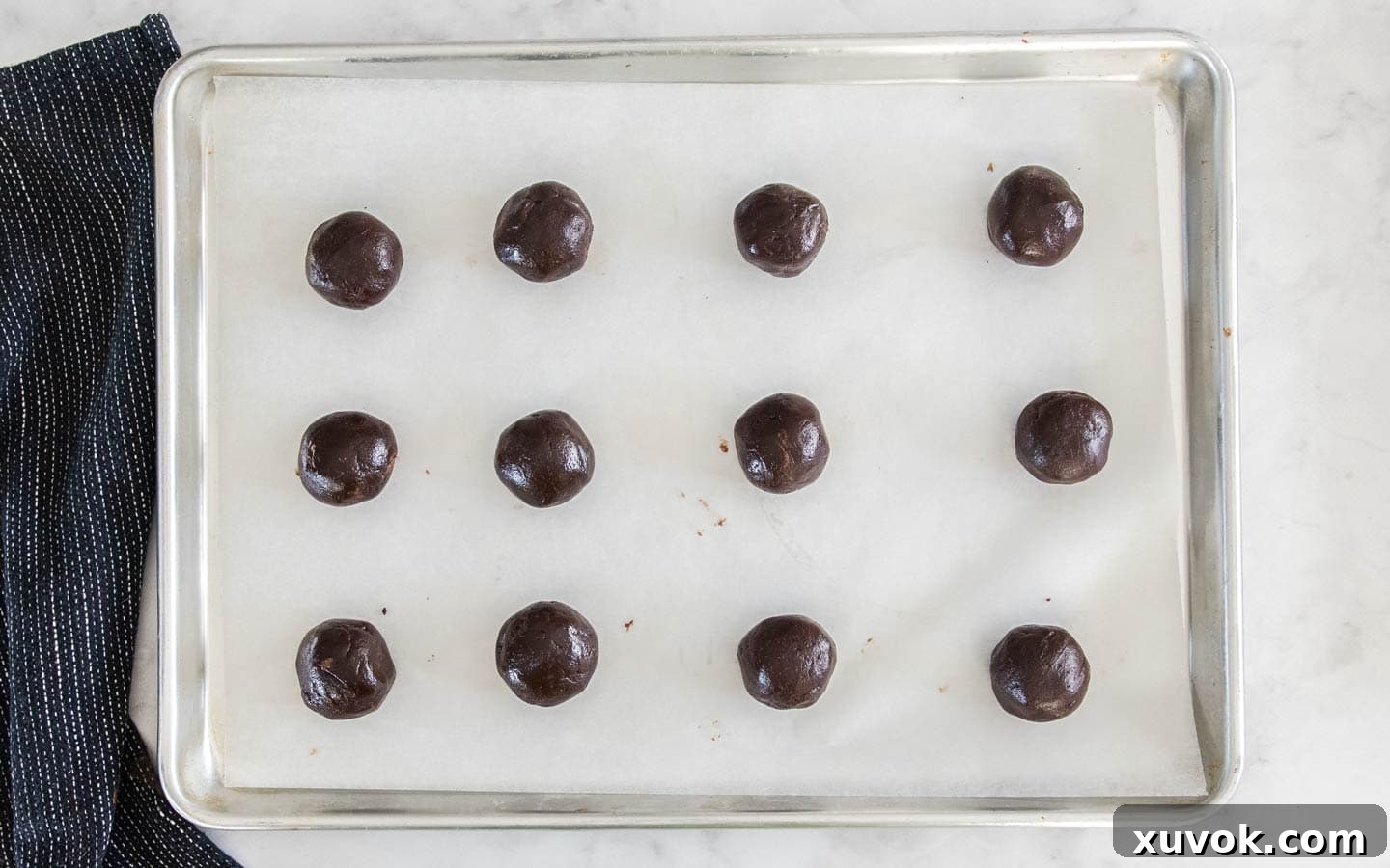 The cookie dough rolled into balls on a baking sheet.