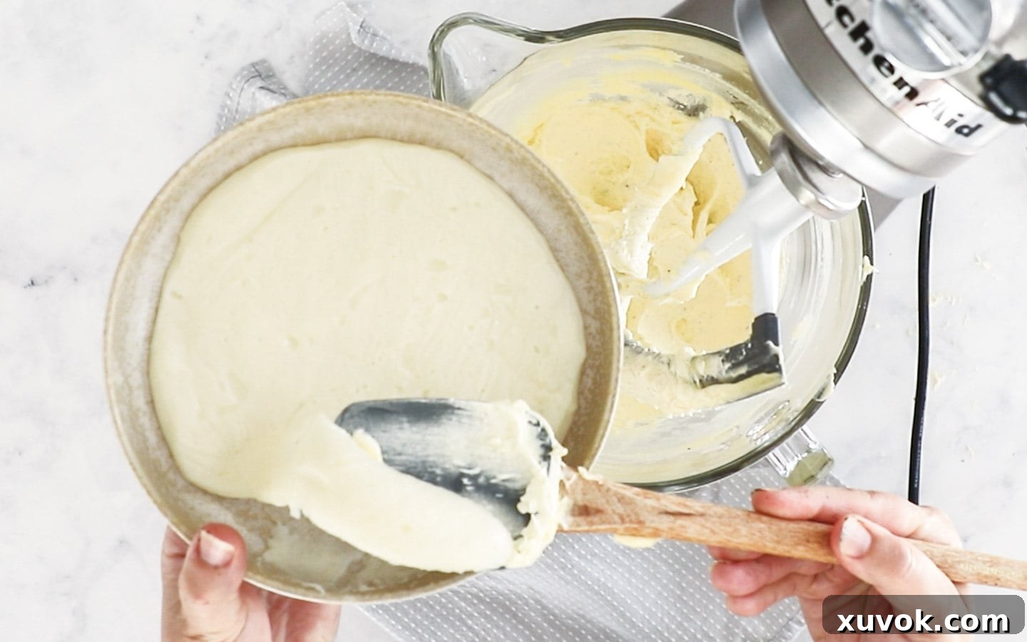 Adding flour and milk pudding to the creamed butter and sugar in a mixer.
