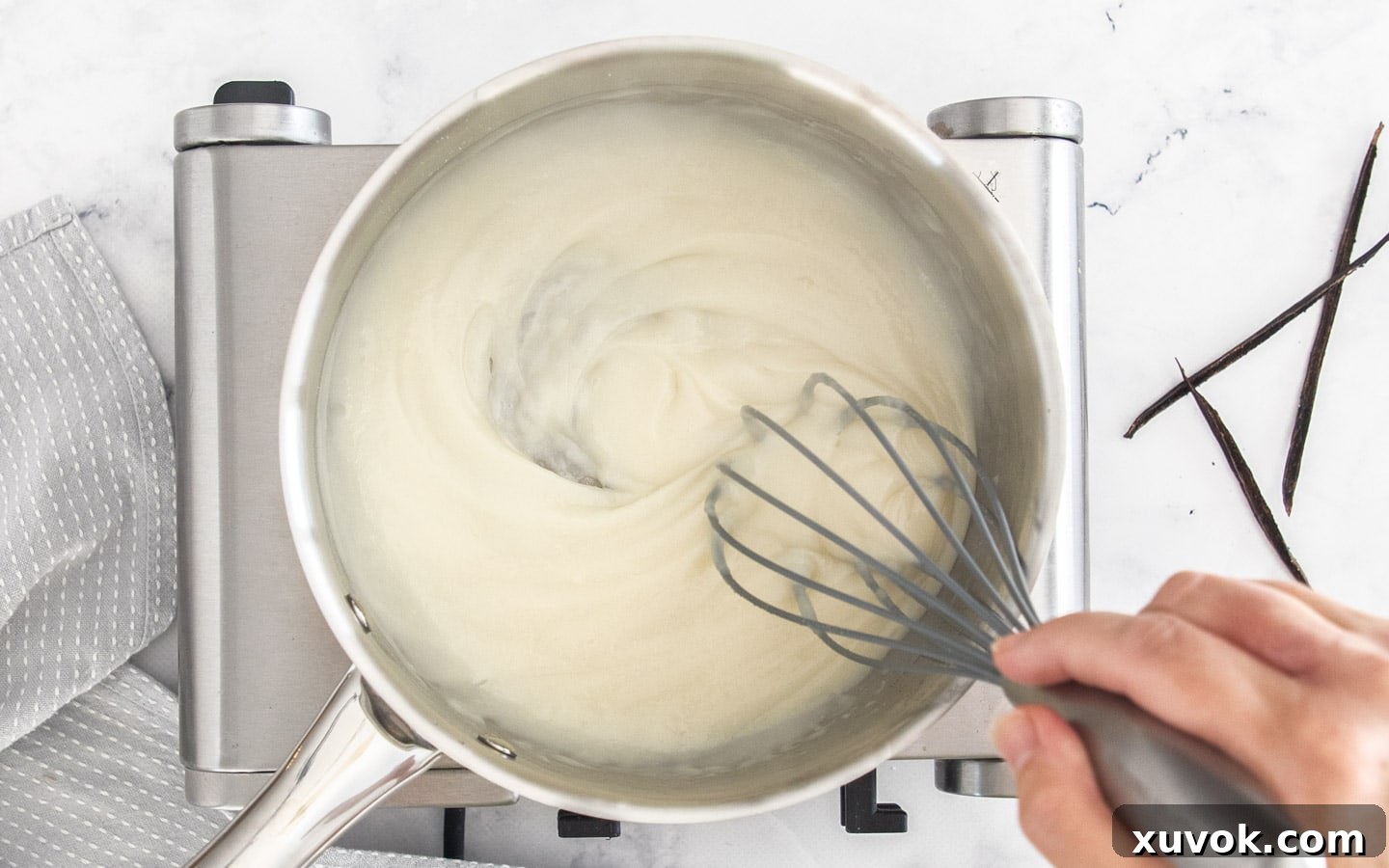 The milk, flour, and sugar mixture being cooked in a saucepan to form a thick pudding base for buttercream.