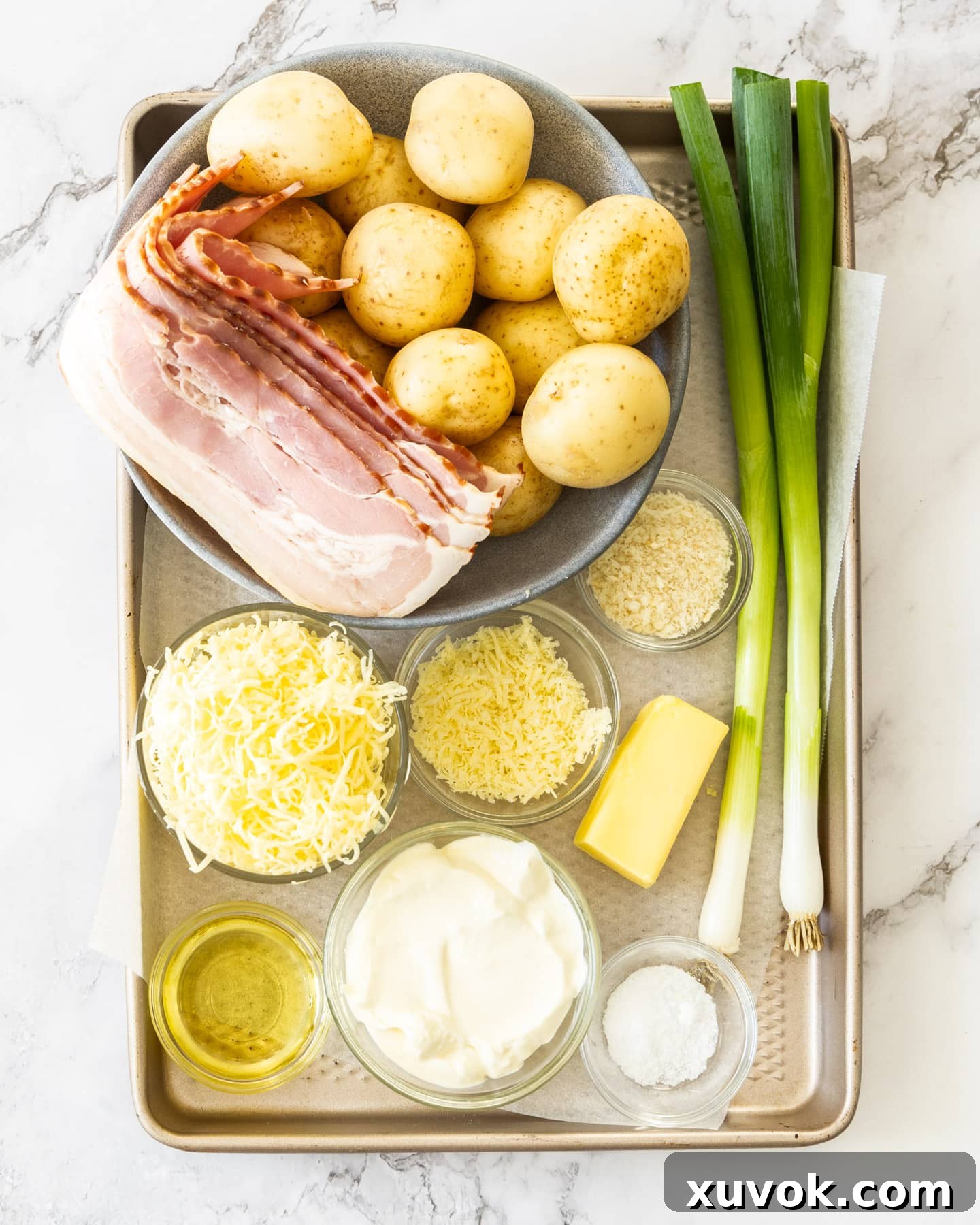 Array of fresh ingredients for mini baked potatoes including baby potatoes, bacon, spring onions, sour cream, and cheese.