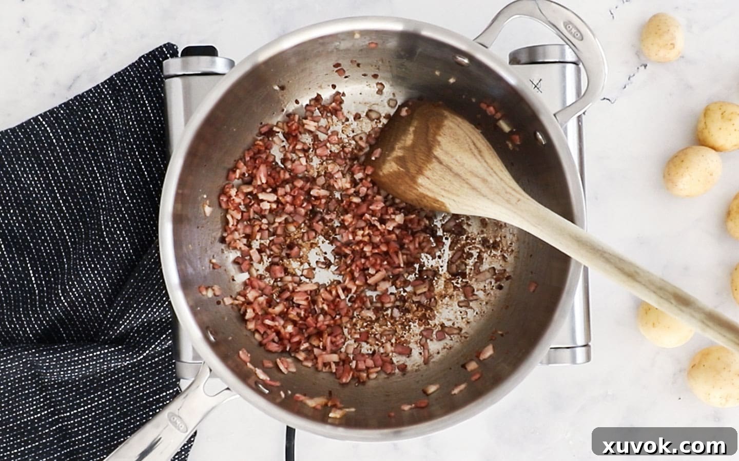 Finely chopped bacon cooking in a sauté pan until golden and crispy.