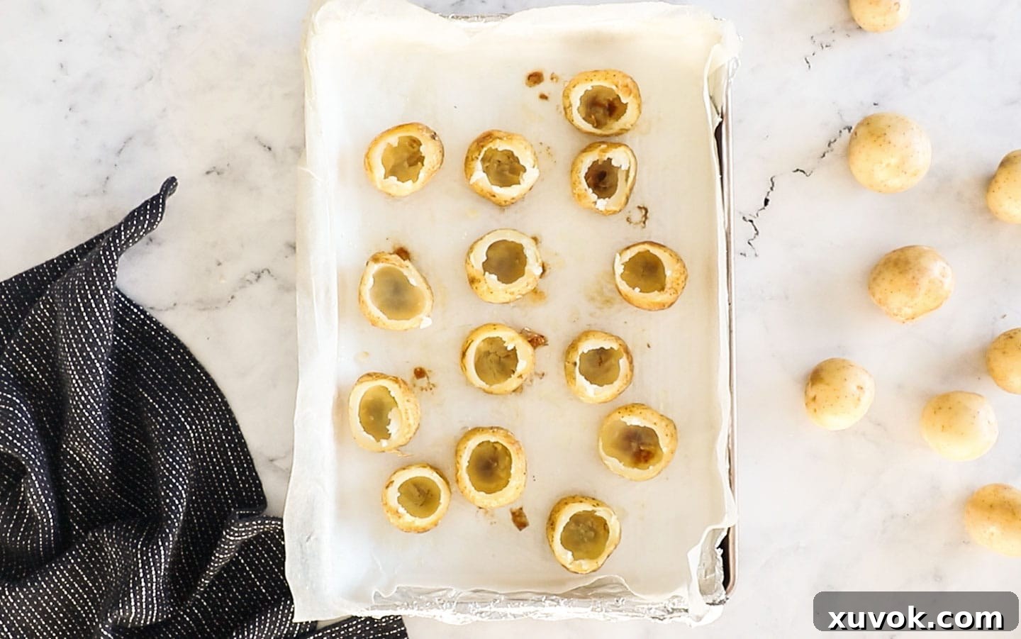 Hollowed-out potato skins on a baking tray, ready to be filled.