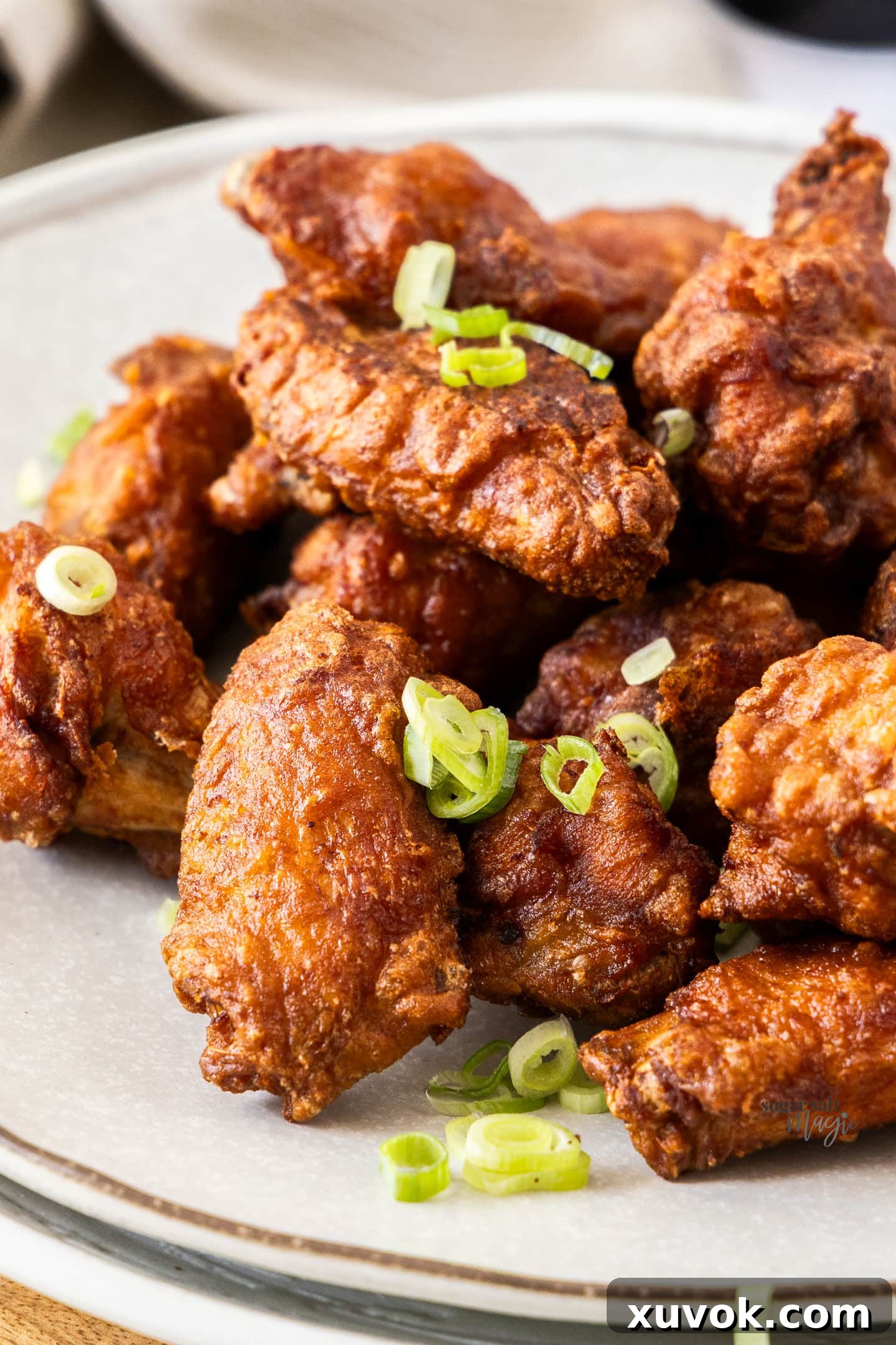 A close-up shot of a batch of golden-brown Chinese fried chicken wings, highlighting their incredibly crispy texture.