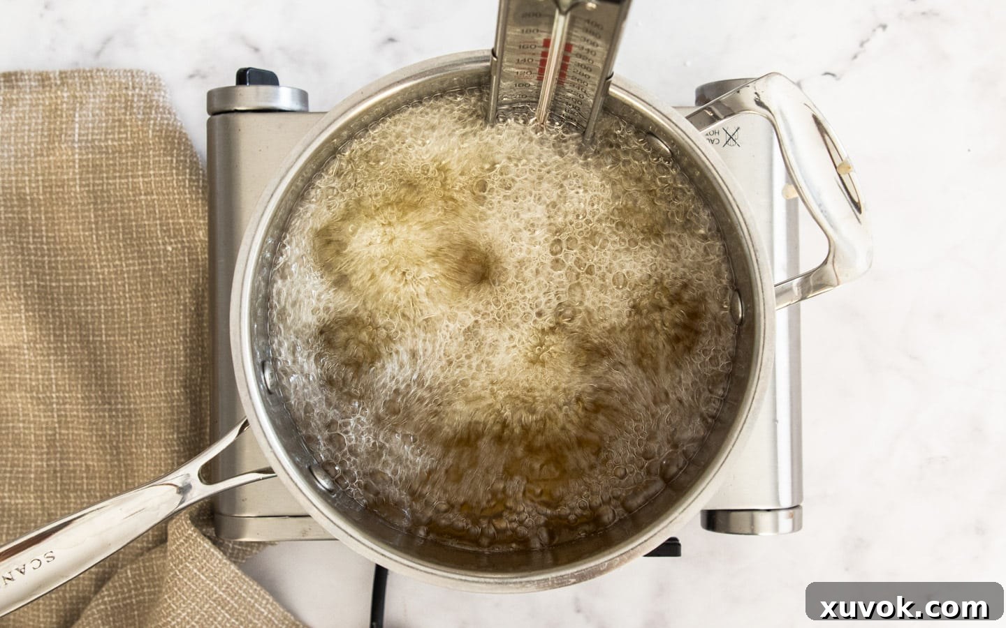 A batch of Chinese fried chicken wings vigorously bubbling in hot oil during their second fry, indicating intense crisping.