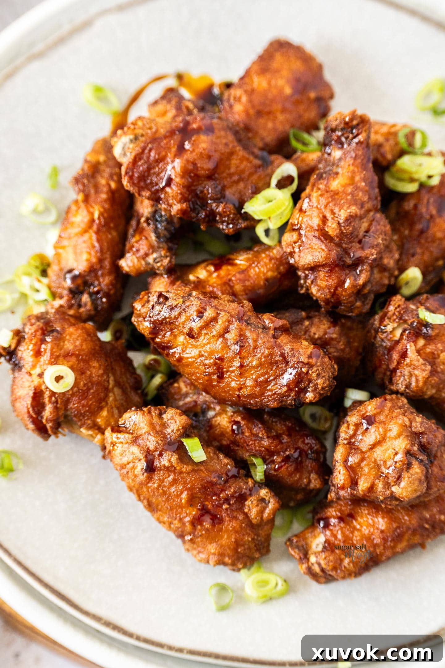 A generous serving of crispy Chinese chicken wings piled on a plate, garnished with fresh herbs, ready to be enjoyed.